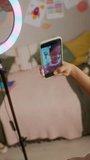 Vertical of African American girl recording video blog on smartphone, waving and showing peace sign. Footage perfect for social media marketing and youth technology campaigns - Powered by Shutterstock - Get 15% off with code: PIKWIZARD15