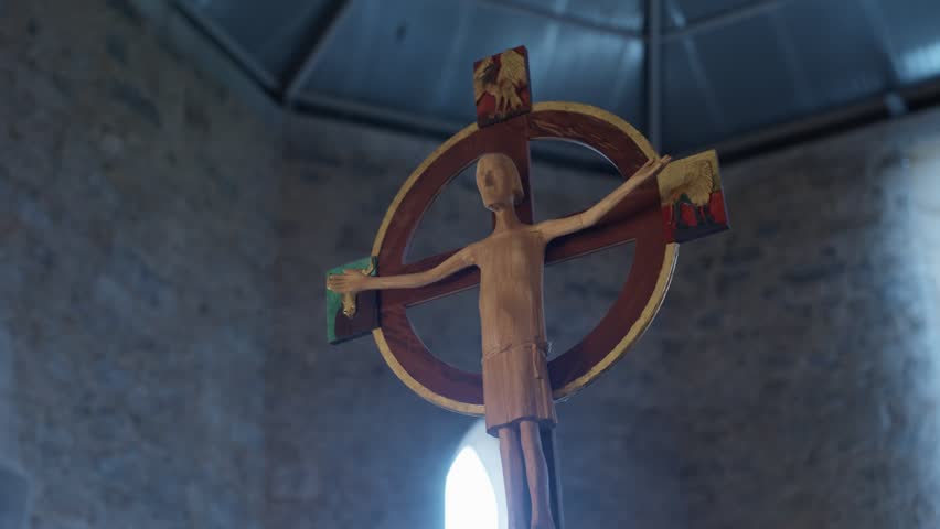 Carved wooden Celtic cross with Christ figure hanging inside stone church
