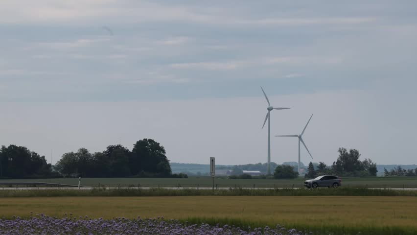 Lund, Sweden A flat farming landscape with a road and wind turbines. 