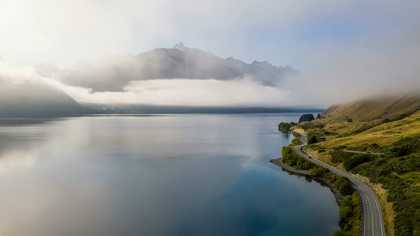 Serene landscape of a winding road along a calm lake with mountains
