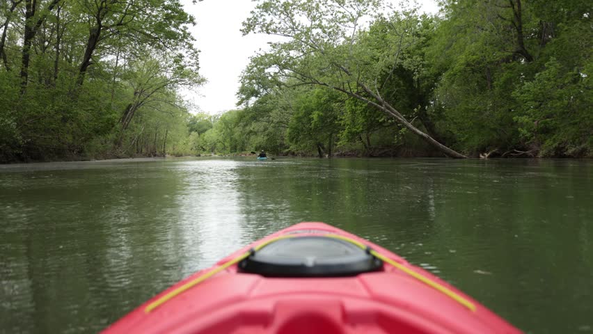 A red kayak drifts serenely down the Meramec River