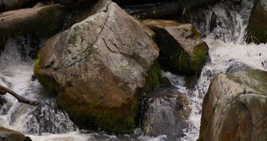 Mountain stream rushing through moss covered boulders