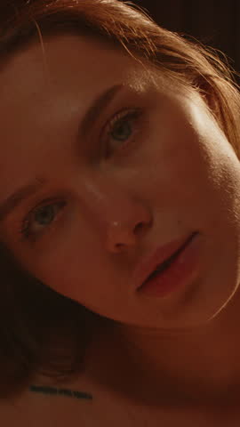 Beautiful vertical close up of a blue eyed young woman sensually looking at the camera in slow motion