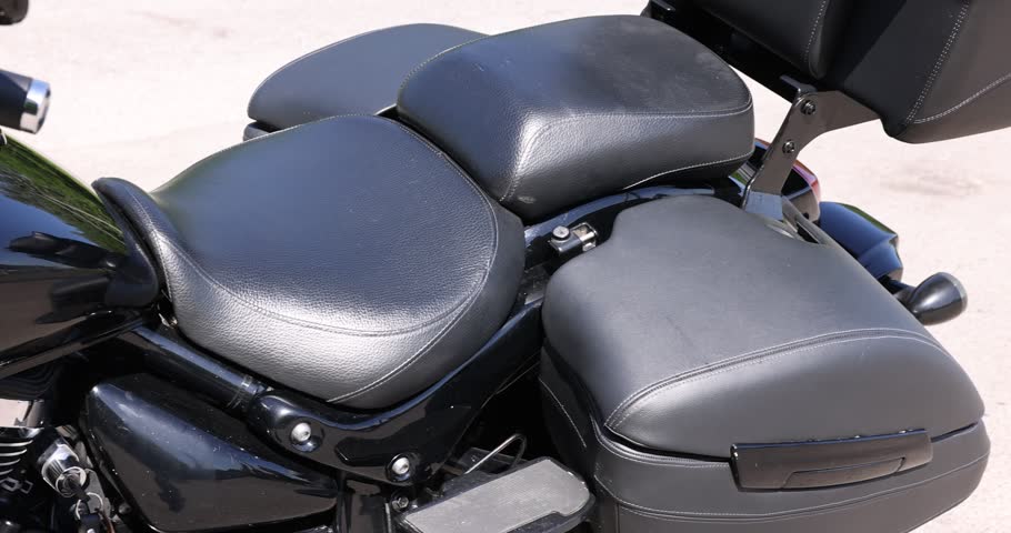 Modern black motorcycle parked on road outdoors, closeup. Camera moving left