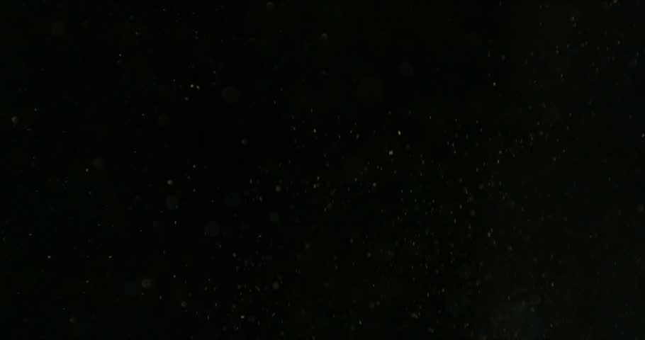 Super slow motion falling snow or dust particles isolated on a black background. Abstract atmospheric SFX overlay with floating debris, cinematic texture and dark visual effect.