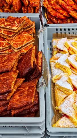 A variety of pastries including rolls, squares, and powdered treats in a bakery.