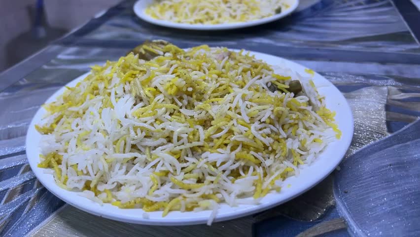 Kolkata style chicken biryani with large leg piece and salad; traditional aromatic basmati rice, iconic calcutta biryani potato, chicken drumstick platter, and Indian street food.