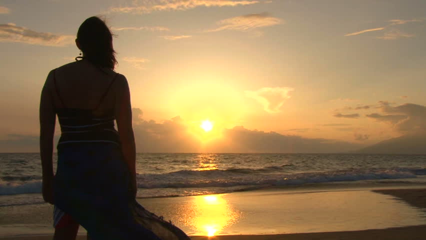 Camera zoom out on model released woman standing on sandy beach during sunset in