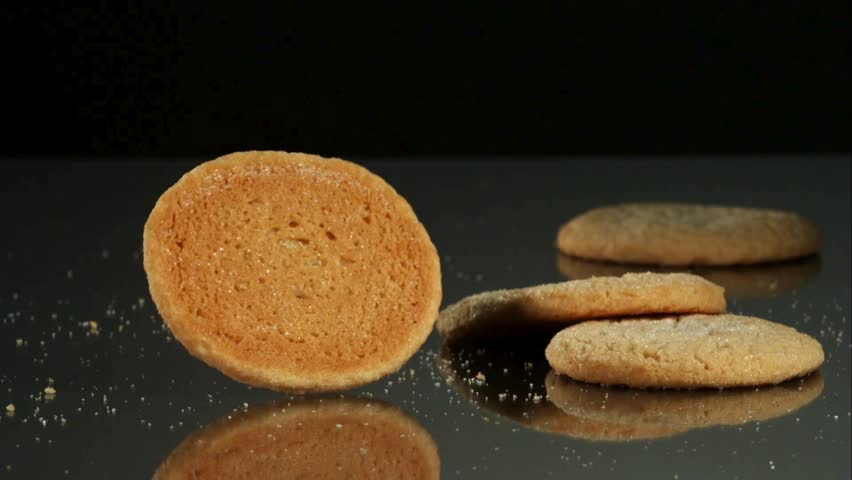 Sugar cookies fall and bounce on a dark surface