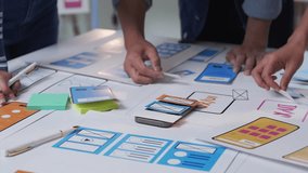 Software engineers collaborating on mobile application design, developing user interface and user experience through paper prototyping with smartphone at creative workspace - Powered by Shutterstock - Get 15% off with code: PIKWIZARD15
