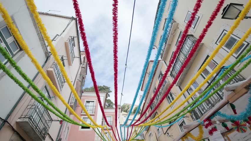 Colorful festive garlands hanging between traditional buildings in a narrow lisbon street in portugal