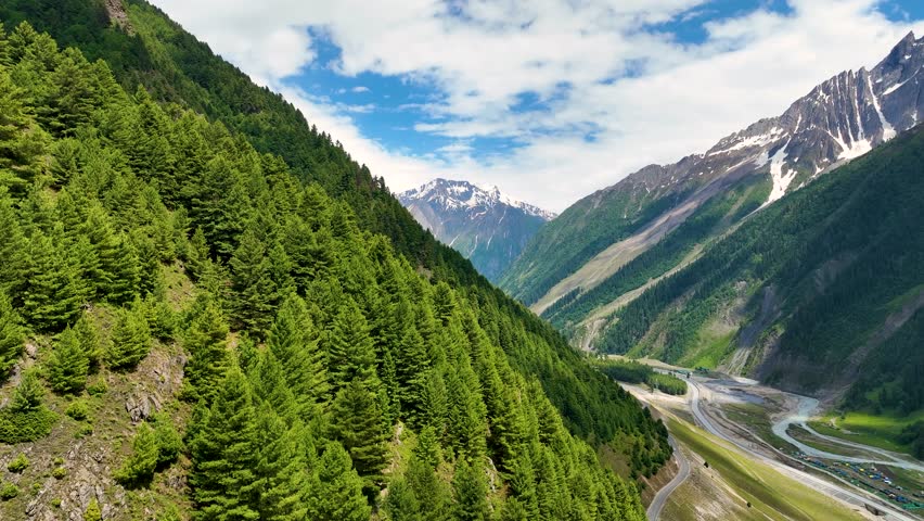 Lush green mountain slopes and winding alpine road in northern India.