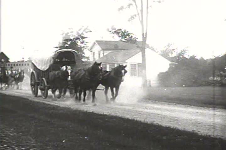 1900s - Stagecoaches and carriages move along a country road. An organ grinder entertains.