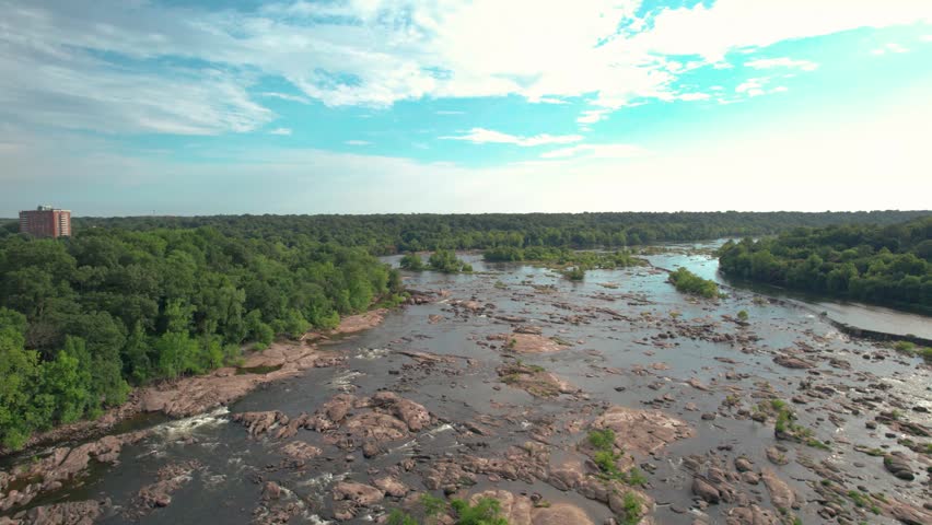 Scenic Aerial View of Wide Rocky River with Rapids and Dense Green Forest Under a Bright Sky