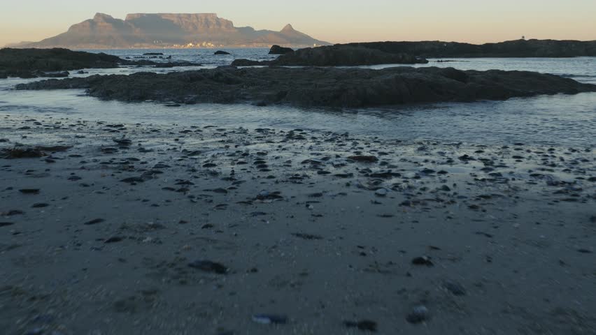 4K 25fps footage from Bloubergstrand showcasing the iconic Cape Town skyline with Table Mountain, Devil’s Peak and Lion’s Head across Table Bay under clear South African blue skies.