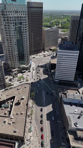 Portage Avenue and Main Street intersection in downtown Winnipeg, Manitoba. Vertical drone moves toward the junction showing traffic, crosswalks, and surrounding buildings on a clear summer daytime.