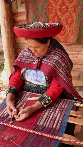 Indigenous Quechua woman weaving colorful threads on a traditional wooden loom in a rural village