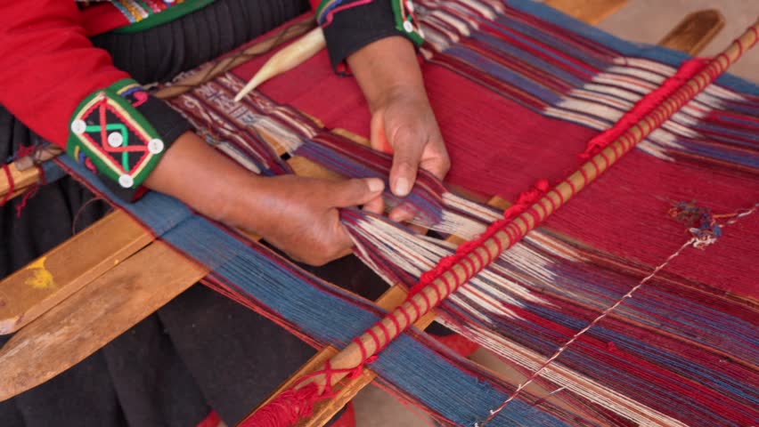 Close-up of indigenous woman weaving colorful textile on a traditional loom