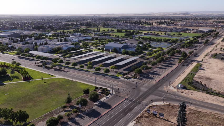 Drone push in showing the modern campus of Clovis Community College in Fresno, California, highlighting its architecture, green spaces, and parking lots with solar panel carports