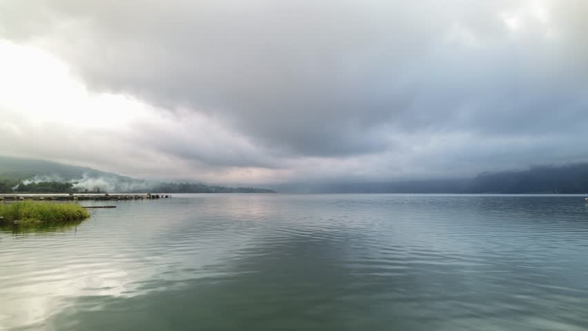 Dramatic Clouds Moving Over Calm Lake and Pier Landscape