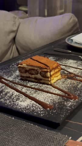 Creamy Tiramisu cake decorated with cocoa powder and chocolate sauce