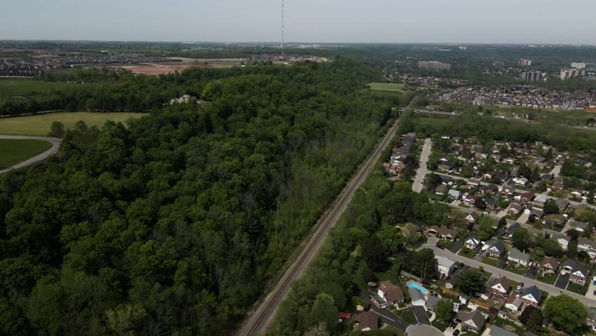 Aerial view of the lush forest and railway tracks bordering a residential neighborhood near the Devil