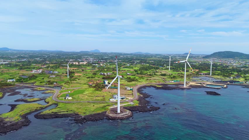Aerial parallax of Sinchang windmill coastal road along volcanic coastline in Hangyeong-myeon, Jeju with Hallasan mountain in background