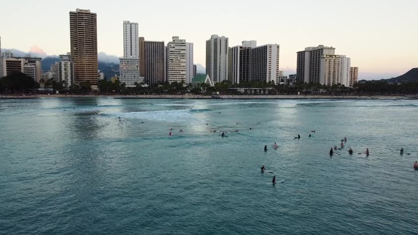 Aerial view of waikiki beach in honolulu, hawaii, with surfers waiting for waves and diamond head in the background during sunset