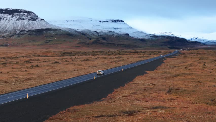 Aerial view of car driving on road by snowy mountains in Iceland
