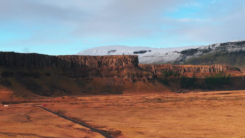 Aerial view of volcanic cliffs and snowy mountain in Iceland