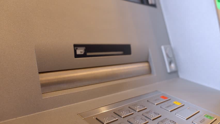 Close-up view of female hands taking one hundred dollar bills from an atm cash dispenser, illustrating a financial transaction and money withdrawal at an automated banking terminal