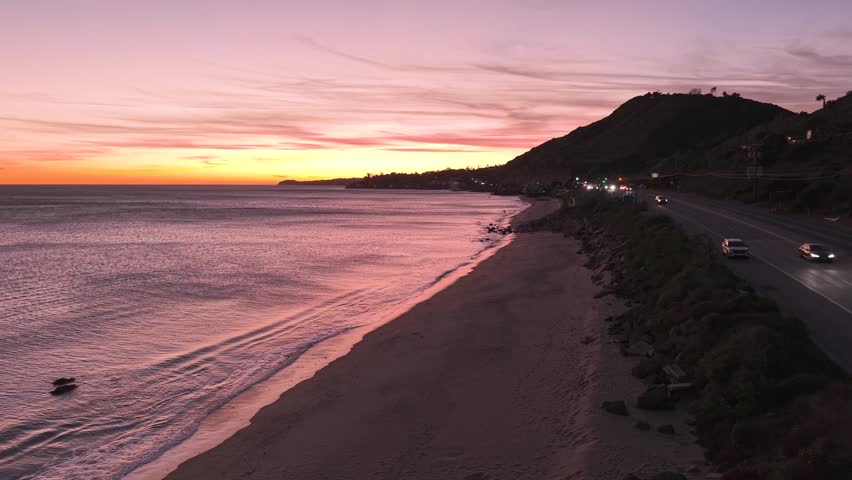 Pacific Ocean horizon at sunset, calm California waters and orange-pink sky, coastal sunset scenery. Warm orange glow on the horizon in the sky.