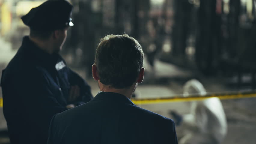 Police officer and detective discussing murder investigation at crime scene