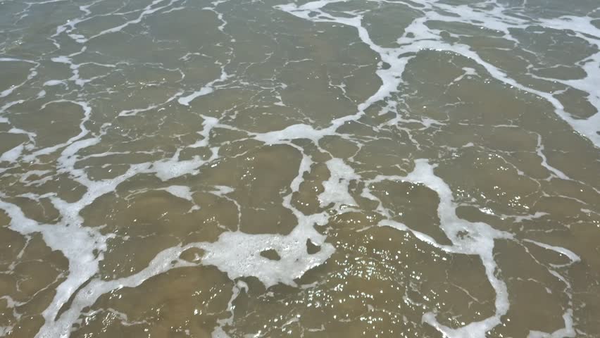 closeup of waves on a sandy beach 