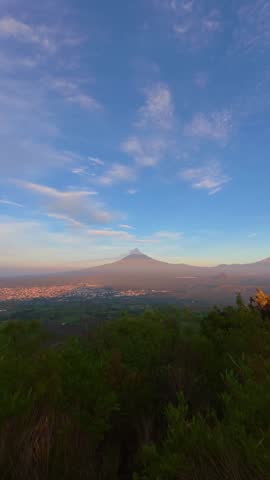 Beautiful sunrise over the popocatepetl volcano in mexico, with a small city at its base