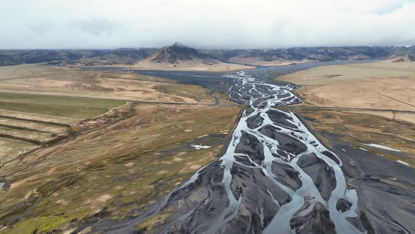 Drone video of braided river and Icelandic landscape on a day with clouds