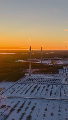 Vertical background of wind turbine beginning to spin above rural farm fields at sunset dusk