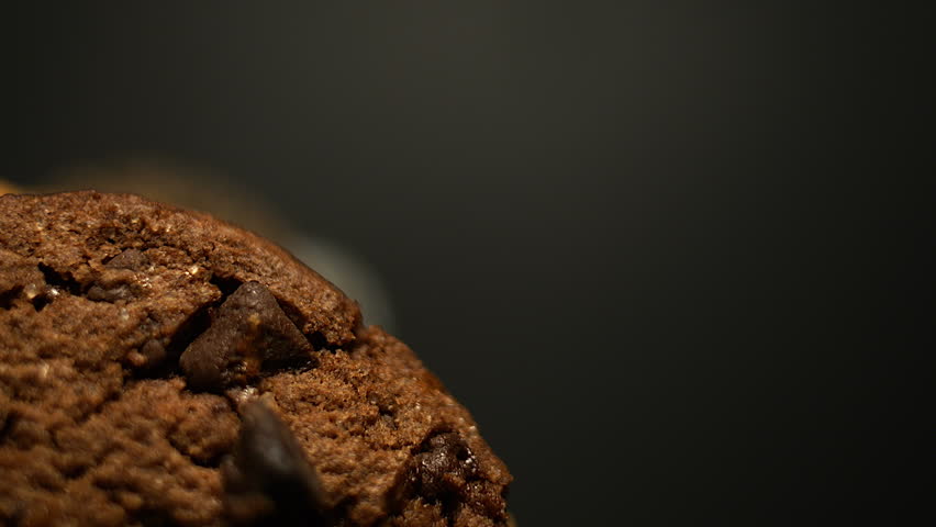 50p macro close up side view shot of a brown cookie rotating to reveal texture, crumbs and baked surface details