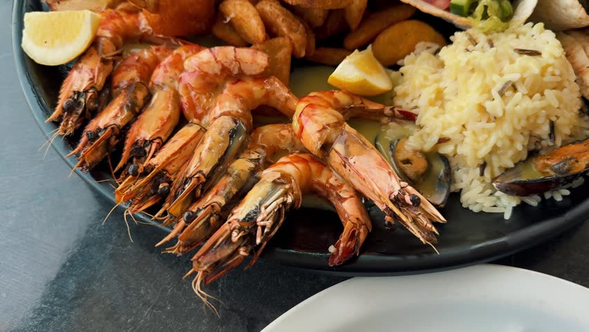 A massive, delectable Greek seafood platter featuring grilled prawns, crispy calamari, fresh mussels, golden fries, rice, and a vibrant Greek salad. Perfect restaurant quality meal.