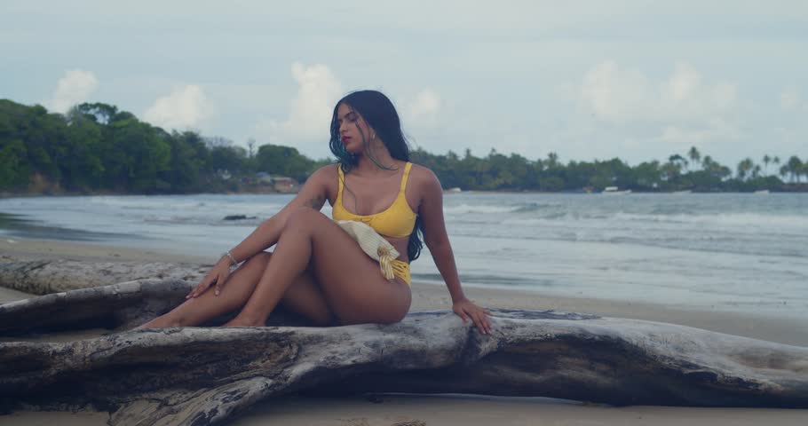 A girl in a yellow bikini standing in the turquoise waters of the tropics.