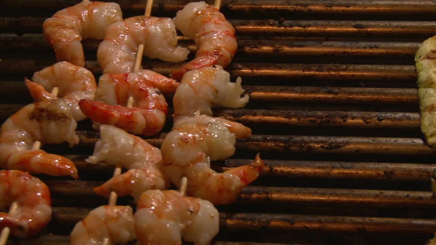 Grilling shrimp kabobs on barbecue at night.
