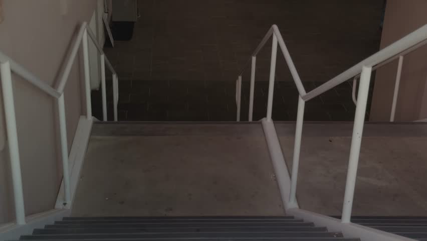 Slow downward pan across an indoor staircase revealing steps, handrails, and lower landing area.