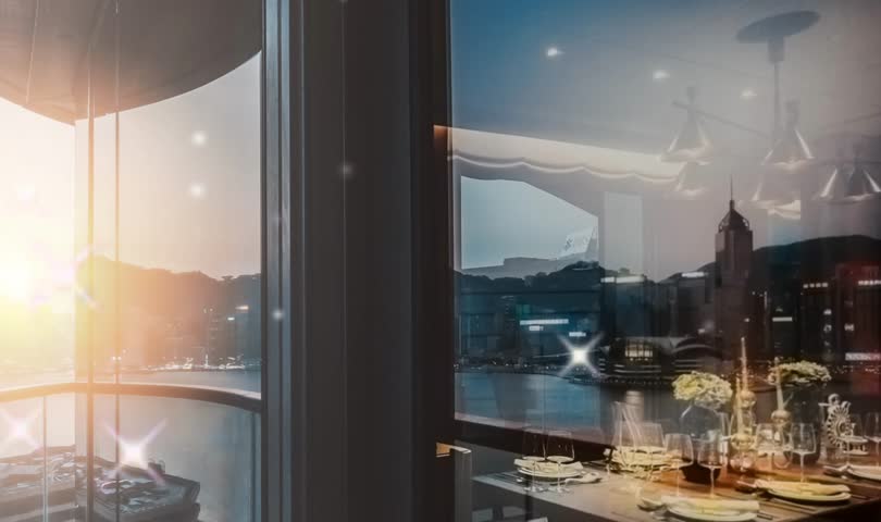 A picturesque moment of a luxurious evening meal under the warm glow of a setting sun, framed by modern architecture and vibrant city lights.