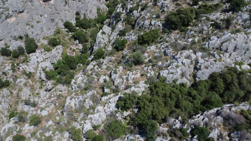 Aerial panorama of a dramatic gorge surrounded by rugged mountains and greenery. The landscape reflects freedom, discovery, adventure and summer exploration in Greece, Europe.