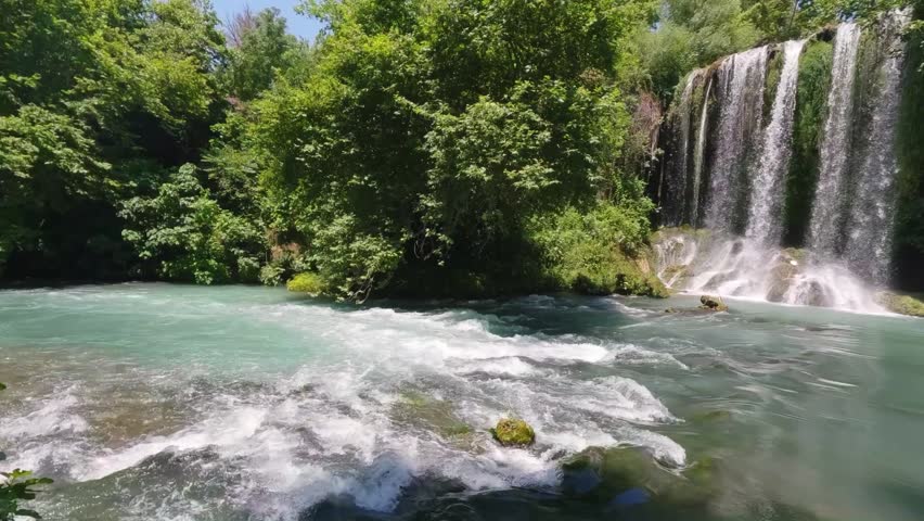 Scenic Waterfall and Rushing Turquoise River Rapids in Green Forest