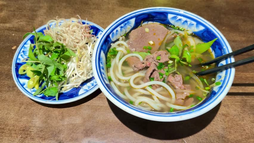 Authentic Vietnamese pho rich broth, tender beef, and silky rice noodles, with chopsticks picking up.