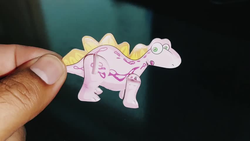Hand Holding Cute Pink Stegosaurus Toy Close Up View