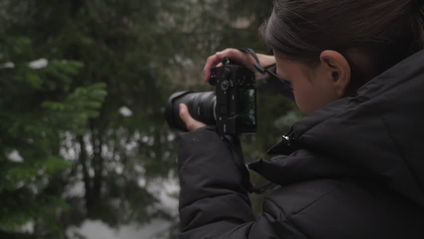 Female photographer taking photos of nature in forest. Outdoor photography process, creative hobby and travel lifestyle.