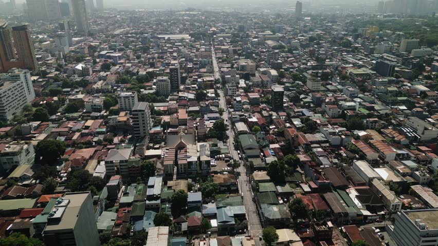 Aerial flyover of San Roque in Quezon City showing dense residential blocks, long roads, and Metro Manila urban sprawl - Philippines