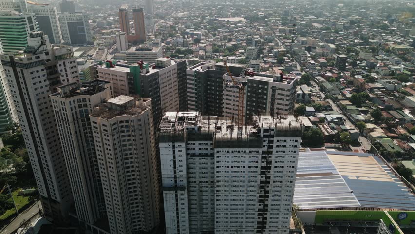 Aerial orbit of condominium towers under construction in Cubao, Metro Manila, surrounded by dense buildings and urban development - Philippines